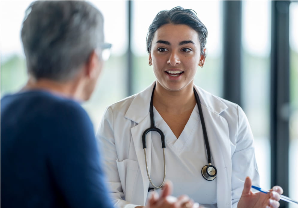A provider sits across their desk and talks to an older adult patient.